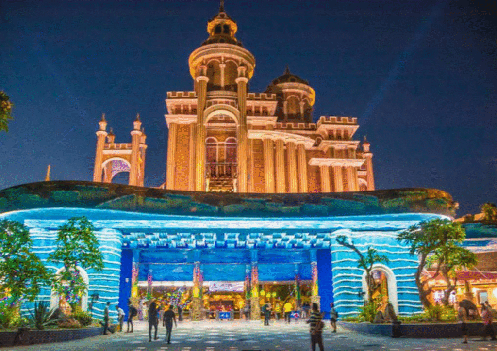 Tampilan malam Atlantis Land di Kenjeran Park dengan gedung megah dan lampu biru yang memukau